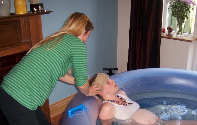 A doula assists in a home water birth